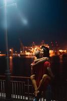 vent en meisje knuffelen elk andere Aan een achtergrond van de nacht haven foto