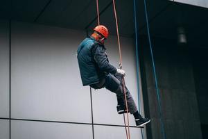 industrieel klimmer in uniform en helm stijgt foto