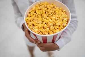 detailopname foto van een jong zoet meisje, wie is Holding een buis van popcorn in haar handen.