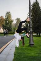 aantrekkelijk mager vrouw aan het doen een achteroverbuigen terwijl tonen een salto. foto