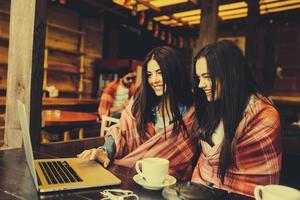 twee meisjes kijken naar iets in de laptop foto