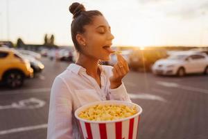 jong schattig vrouw Holding popcorn in een boodschappen doen winkelcentrum parkeren veel foto