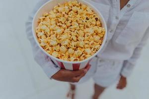 detailopname foto van een jong zoet meisje, wie is Holding een buis van popcorn in haar handen.