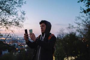 jong vent in de park duurt een foto Aan twee smartphones
