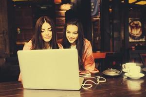 twee meisjes kijken naar iets in de laptop foto