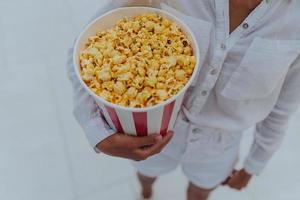 detailopname foto van een jong zoet meisje, wie is Holding een buis van popcorn in haar handen.