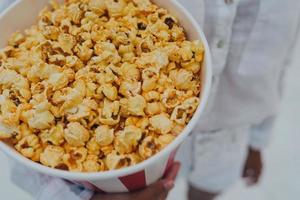 detailopname foto van een jong zoet meisje, wie is Holding een buis van popcorn in haar handen.