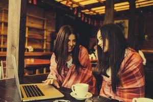 twee meisjes kijken naar iets in de laptop foto