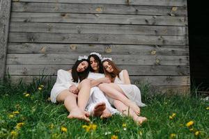 drie charmant meisjes in de buurt een houten huis foto