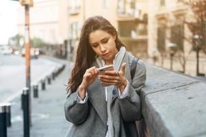 vrouw gebruik makend van haar mobiel telefoon in de straat. foto