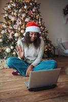 vrouw vervelend de kerstman hoed terwijl sprekend met online vriend Aan laptop foto