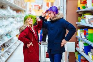 jong paar voor de gek houden in de omgeving van met kommen in een supermarkt foto