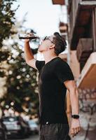 jong aantrekkelijk hipster Mens Aan de straat drankjes een koel drinken Aan een zomer dag. foto