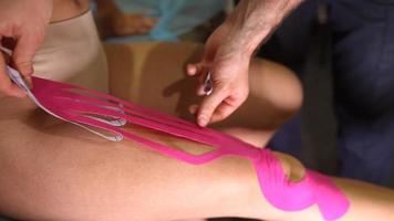 fysiotherapeut toepassen kinesio plakband Aan vrouw geduldig. foto
