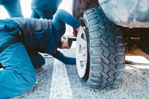 Mens verandering de wiel handmatig Aan een 4x4 uit weg vrachtauto foto