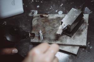 in de werkplaats, een vrouw juwelier is bezig solderen sieraden foto