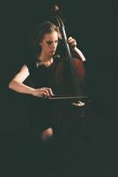 mooie jonge vrouw die 's nachts een cello speelt