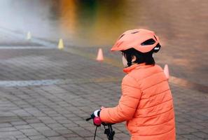 school- kind leert naar rijden een fiets in de park, buitenshuis portret van een jong jongen Aan fiets, kind in helm rijden een wielersport in de ochtend. foto