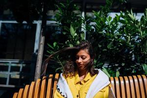 brunette meisje zittend Aan bank in centraal een deel van oud stad. foto