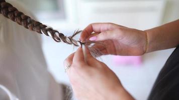 werkwijze van vlechten. meester weeft vlechtjes Aan hoofd in een schoonheid salon, dichtbij omhoog foto