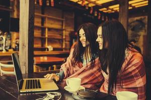 twee meisjes kijken naar iets in de laptop foto