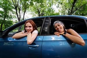 twee vriendinnetjes dwaas in de omgeving van en lachend samen in een auto foto