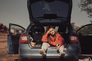 aantrekkelijk jong vrouw resting in de romp van een auto foto