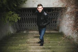 een Mens gekleed in jeans en zwart jasje Aan authentiek trap foto