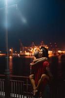 vent en meisje knuffelen elk andere Aan een achtergrond van de nacht haven foto