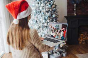 vrouw vervelend de kerstman hoed terwijl sprekend met online vriend Aan laptop foto