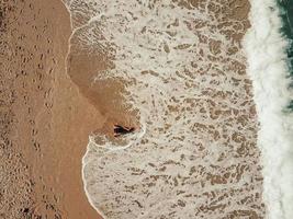 antenne top visie jong vrouw aan het liegen Aan de zand strand en golven foto