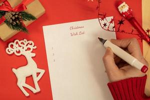 vrouw hand- houdt een pen over- een wit vel van papier naar schrijven naar beneden doelen voor de jaar of teken een Kerstmis kaart foto