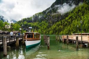 toneel- visie Aan konigssee meer met houten pier met afgemeerd toeristisch schip foto