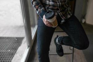 Zelfverzekerde man poseren in zelfkant jeans, kopje koffie te houden foto