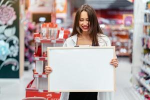 glimlachen brunette vrouw Holding wit blanco bord foto