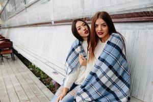 twee meisjes zitten Aan een bank in de park foto