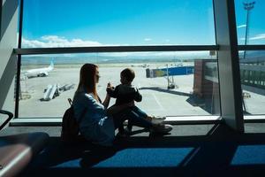 weinig jongen en zijn moeder zittend in een luchthaven foto