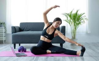 portret van jong mooi Aziatisch vrouw uitrekken warm omhoog oefening training yoga positie Bij huis in leven kamer. sportief Azië meisje Gezondheid zorg levensstijl. foto