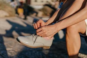 jong vrouw koppelverkoop haar schoenen in de park foto