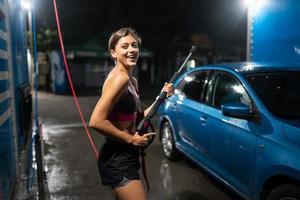 jong vrouw het wassen blauw auto Bij auto wassen foto