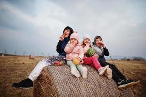 vier kinderen met fruit in handen zittend op haycock op veld. foto