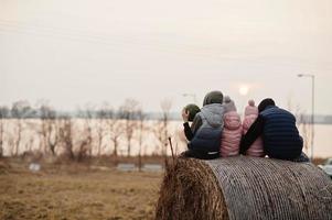 achterkant van vier kinderen zittend op hooi in het veld tegen de zonsondergang aan het meer. foto