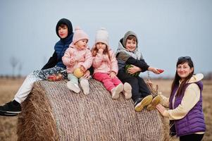 vier kinderen met moeder plezier op haycock op veld. foto