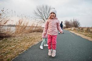 kinderen springen Aan de pad door de meer. foto