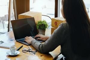 werk van huis. gelukkig Dames verkoop producten online begin een klein bedrijf eigenaar door gebruik makend van laptop computer naar berekenen prijzen en bereiden voor port. foto