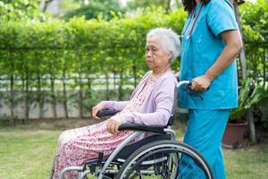 arts verzorger hulp en zorg Aziatische senior of oudere oude dame vrouw patiënt zittend op rolstoel in park in verpleegziekenhuis, gezond sterk medisch concept foto