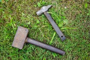 een bouw gereedschap een hamer en een voorhamer zijn aan het liegen Aan de gras foto