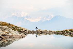 vrouw figuur solo springen van steen naar rots Aan klif gezichtspunt wandelen onderzoeken bergen in vallen Kaukasus reeks achtergrond in racha, Georgisch regio. udziro meer wandelen spoor foto