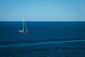 jacht in de blauw zee achtergrond, klein zeilboot avontuur, zeegezicht, boot reizen door de diep oceaan horizon. foto