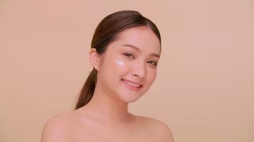 mooi gezicht van Aziatisch jong vrouw met natuurlijk huid. portret van een meisje toepassen vochtinbrengende crème room op haar gezicht. foto